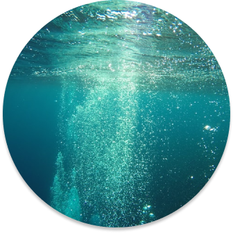 Image of air bubbles in a body of teal coloured water.